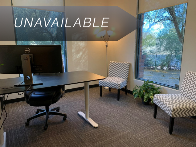 Private office Suite 110 featuring a sit-stand desk, ergonomic chair, and large windows with desert views.