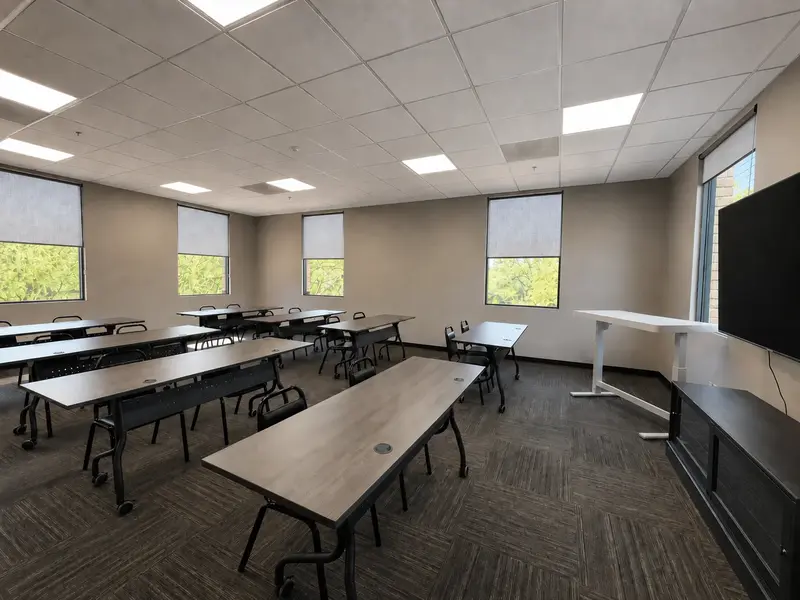 The Flex Space meeting and training room with classroom tables, seating, and presentation screen at Spoke Coworking.