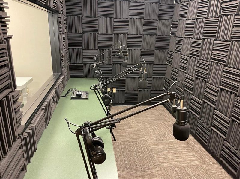 Professional soundproof podcast studio with three microphones and a mixing board in The Podcast Room.