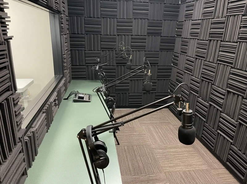 Professional soundproof podcast studio with three microphones and a mixing board in The Podcast Room.