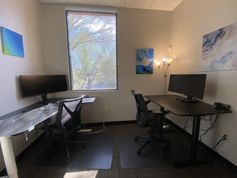 Private Junior Suite 111 office featuring two sit-stand desks, curved monitors, and a large window with a view.