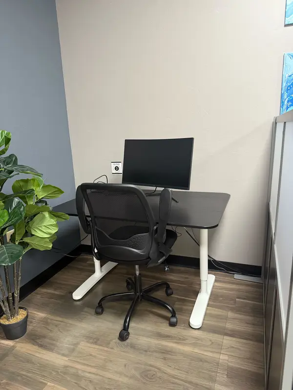 Semi-private Hot Desk 2 in a Tucson coworking space with a curved monitor and ergonomic chair for focused work.