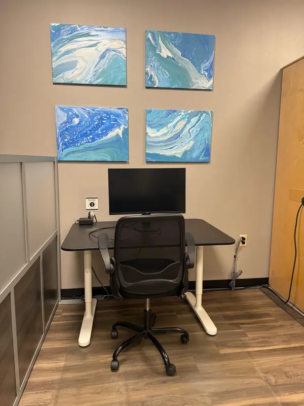 Semi-private Hot Desk 3 in a Tucson coworking space featuring a large monitor and ergonomic office chair.