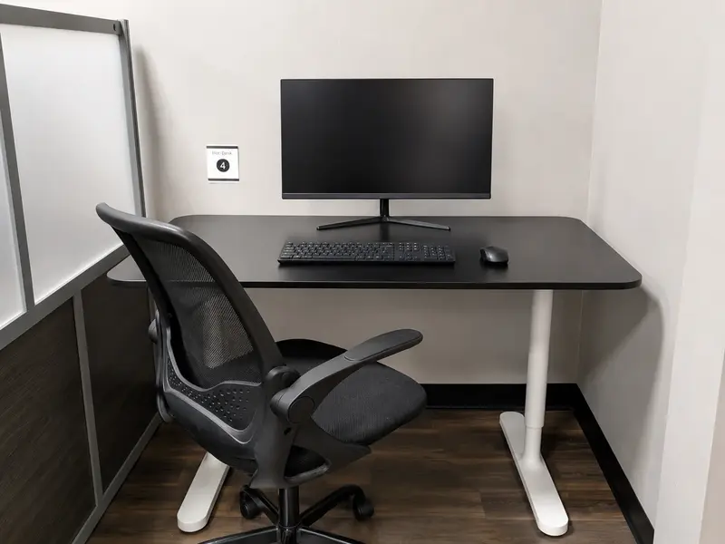 Semi-private Hot Desk 4 with monitor, ergonomic chair, and privacy divider at Spoke Coworking in Tucson.