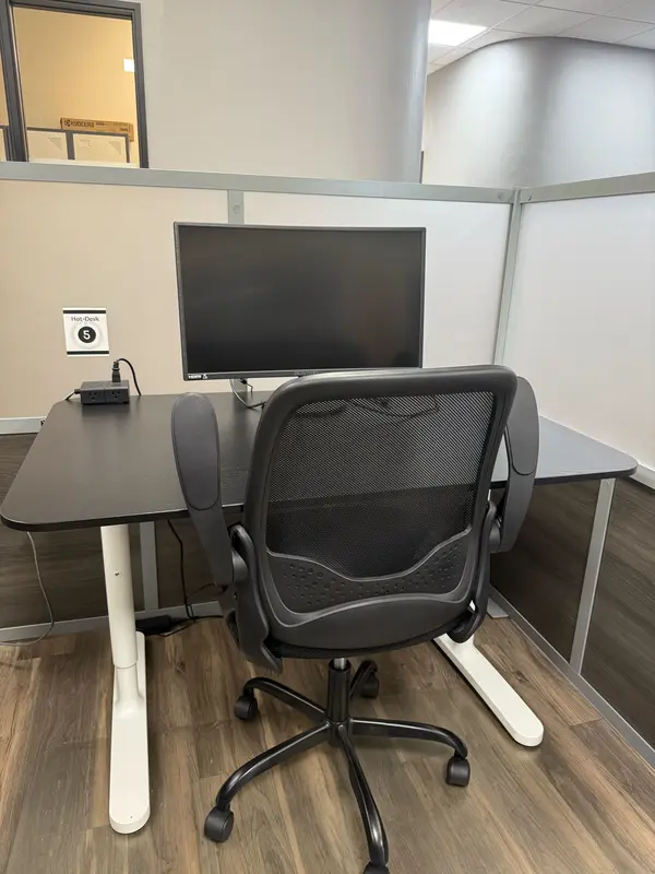 Semi-private Hot Desk 5 setup in Tucson featuring a curved monitor, desk power hub, and ergonomic office chair.