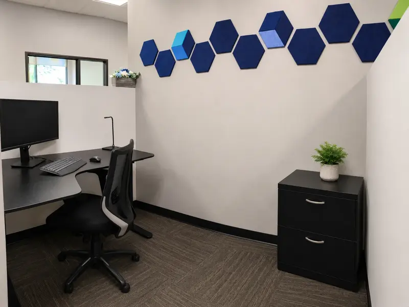 Dedicated Desk 204 workspace featuring an ergonomic sit-stand desk, curved monitor, and file cabinet at Spoke Coworking.
