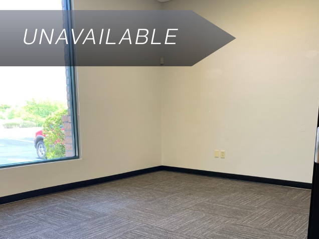 Empty private team office Suite 101 with a large window and grey carpet, currently marked as unavailable.