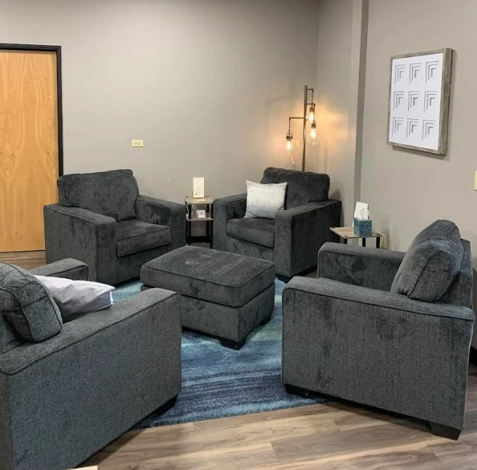 Comfortable lounge seating with large grey armchairs and an ottoman in a Tucson shared workspace.