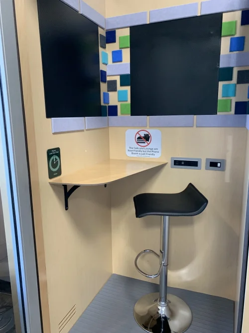 A private soundproof phone booth at Green Booth with a sit-stand stool, desk, and power outlets for focused work.