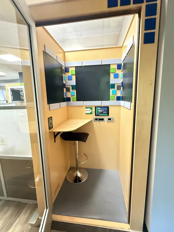 A private soundproof phone booth at Blue Booth with a desk and adjustable stool for quiet video calls and focused work.