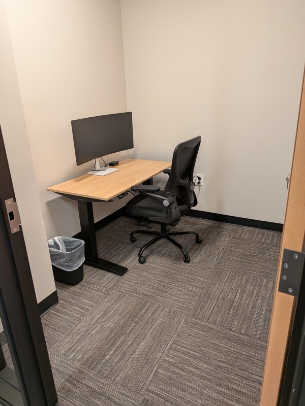 Private Micro Suite 136 with a sit-stand desk, curved monitor, and ergonomic chair for focused individual work.