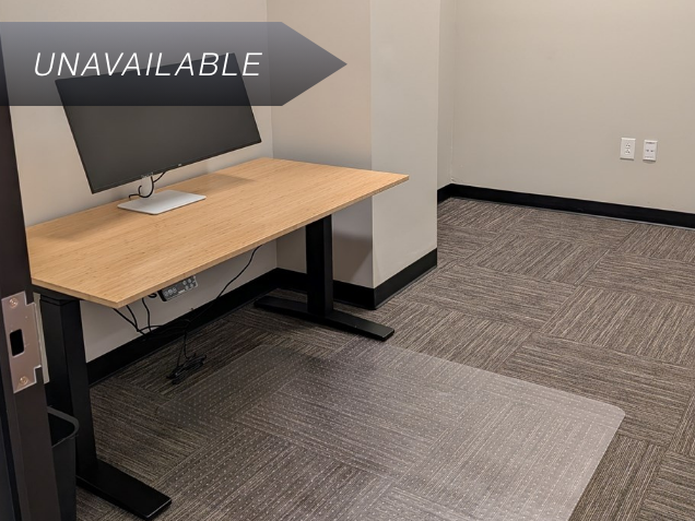 Private office Suite 112 featuring an electric bamboo sit-stand desk and a 34-inch curved monitor.