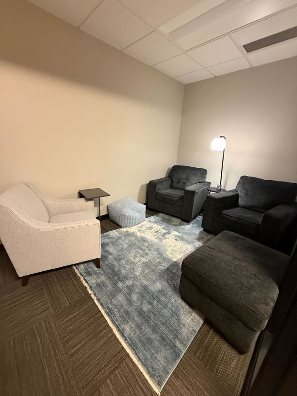 A cozy private therapy office in Suite 126 Huddle Hub with comfortable armchairs and a blue rug for client sessions.