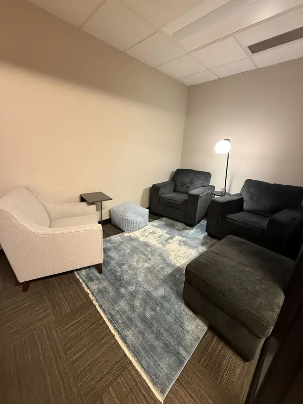 A cozy private therapy office in Suite 126 Huddle Hub with comfortable armchairs and a blue rug for client sessions.