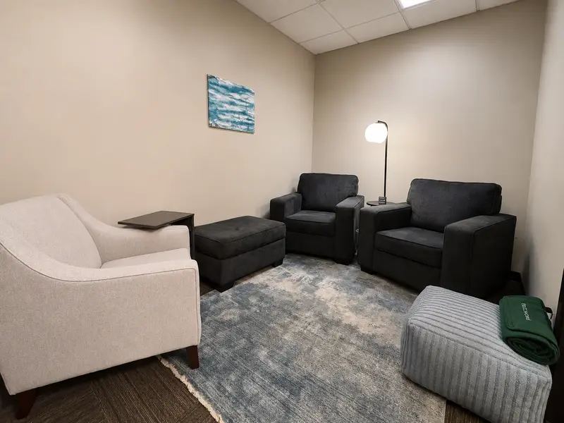 Comfortable private therapy office in Suite 126 Huddle Hub featuring cozy armchairs and a blue area rug.