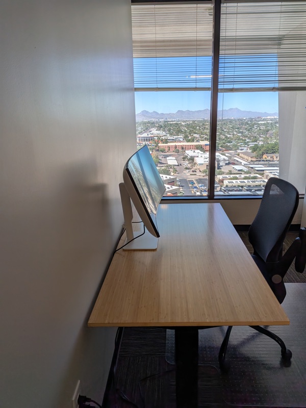 Private office Suite 156 in Tucson with a bamboo sit/stand desk, curved monitor, and sweeping mountain views.