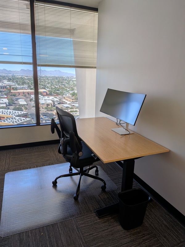 Private office Suite 153 in Tucson featuring a bamboo sit/stand desk, curved monitor, and sweeping city views.
