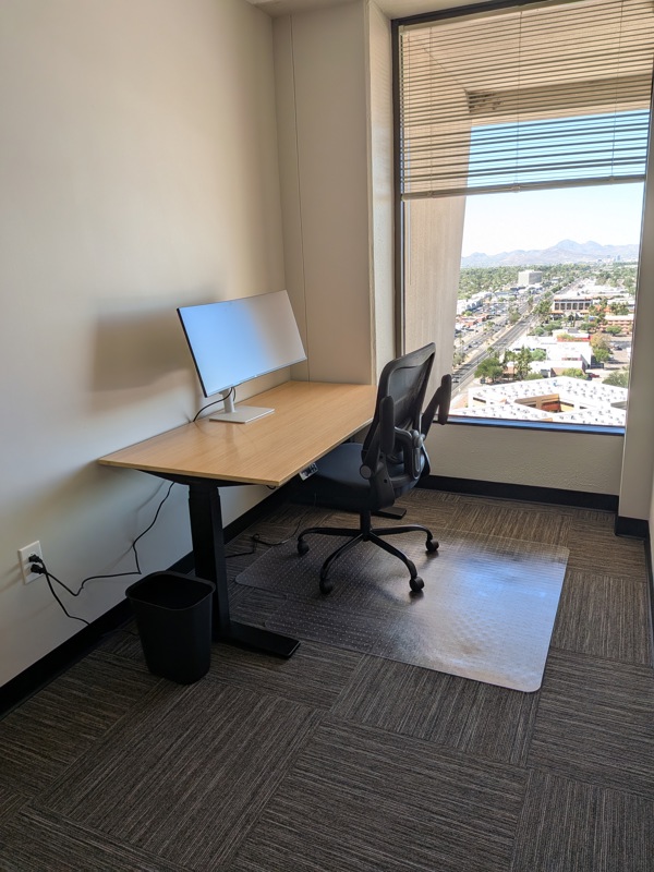 Private office Suite 151 in Tucson featuring a bamboo sit/stand desk, curved monitor, and city views.