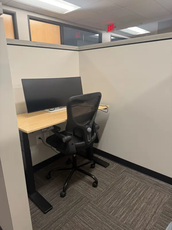 Semi-private dedicated desk 212 at Spoke Coworking with an electric bamboo sit-stand desk and a 36-inch curved monitor.