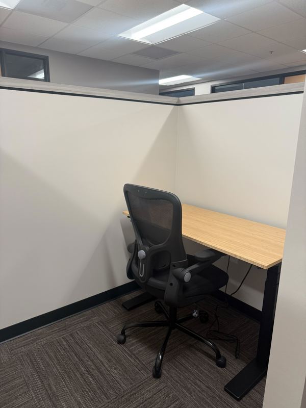 Semi-private dedicated desk 214 at Spoke Coworking with a bamboo sit-stand desk and ergonomic mesh chair.