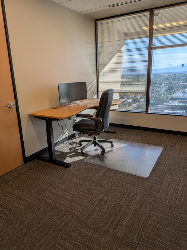 Private executive office Suite 124 featuring a sit-stand desk and large window with scenic mountain views.
