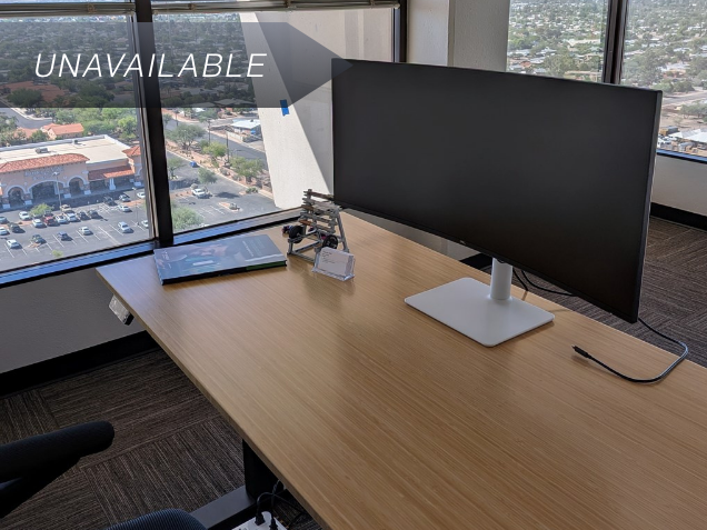 Ergonomic bamboo sit-stand desk and curved monitor in Suite 149 with a 17th-floor corner view of Tucson.