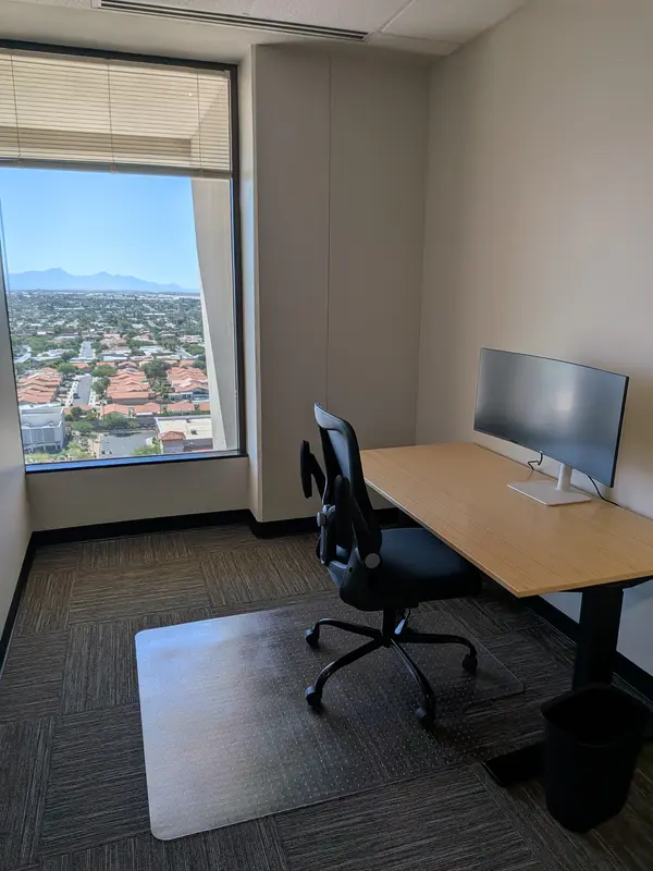 Private office Suite 147 in Tucson with a bamboo sit-stand desk, curved monitor, and scenic mountain and city views.