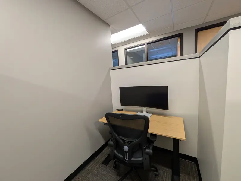 Semi-private dedicated desk 207 with a bamboo sit/stand desk and 34-inch curved monitor for focused work.