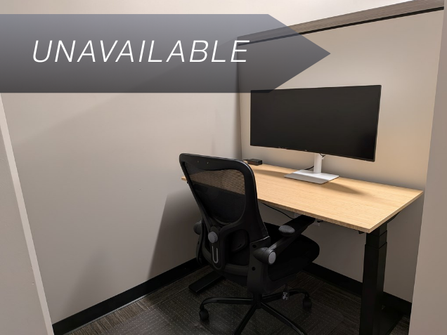 Semi-private dedicated desk 209 with a bamboo sit-stand desk and curved monitor for a productive workspace.