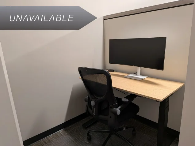 Semi-private dedicated desk 209 featuring a bamboo sit-stand desk and curved monitor in a quiet workspace.