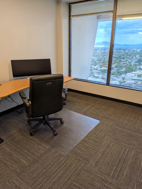 Private executive office Suite 131 featuring a bamboo sit-stand desk, curved monitor, and scenic mountain views.