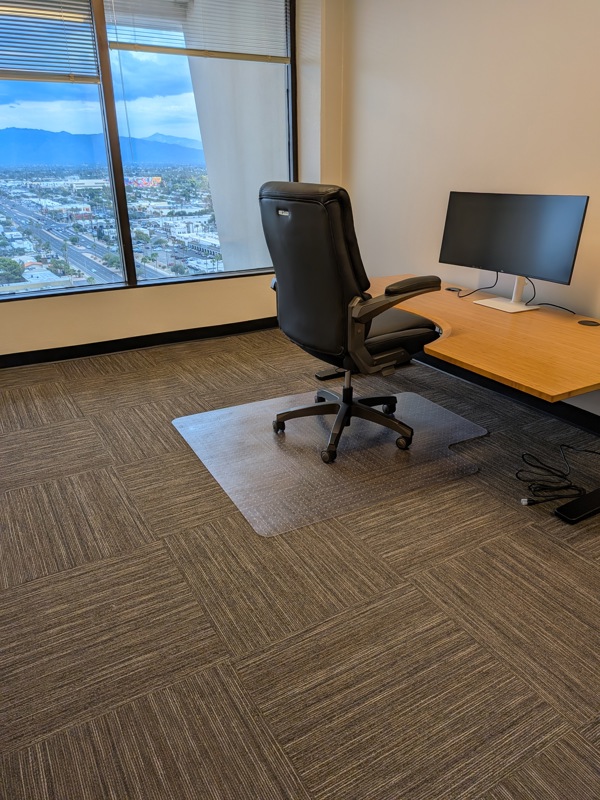 Private executive office Suite 133 with a bamboo sit-stand desk, curved monitor, and scenic mountain views.
