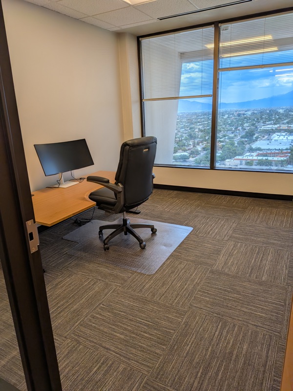 Private executive office Suite 137 with a bamboo sit-stand desk, curved monitor, and panoramic mountain views.