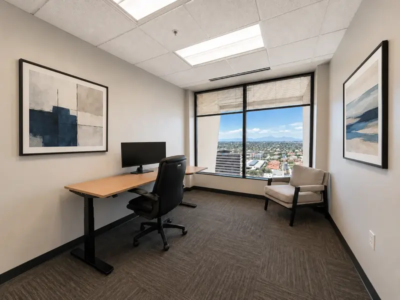 Private executive office Suite 141 at Spoke Tower Suites featuring a sit-stand desk and panoramic Tucson city views.