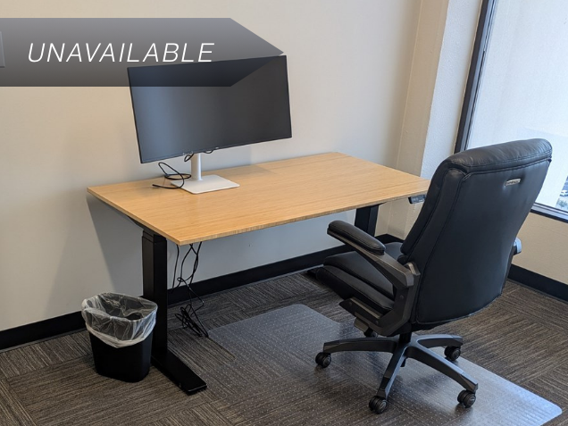 Private Executive Suite 142 with a bamboo sit-stand desk and a 34-inch curved monitor for a productive workspace.