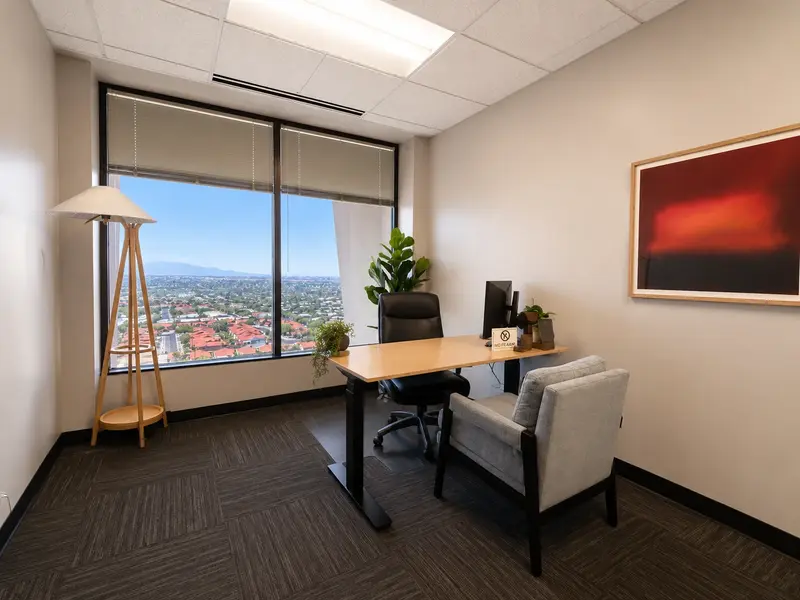 Private executive office Suite 143 at Spoke Tower Suites featuring a sit-stand desk and panoramic Tucson city views.