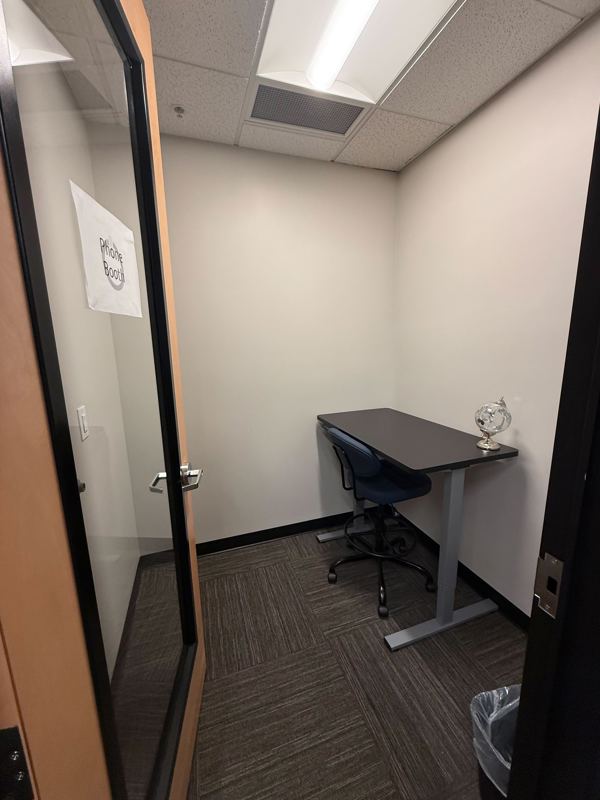 A private soundproof phone booth at Blue Booth with a desk and ergonomic chair for quiet calls and focused work.