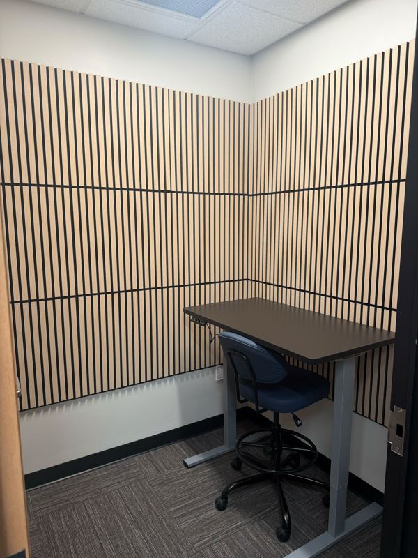 A private soundproof phone booth at Blue Booth featuring a sit-stand desk and blue ergonomic chair for focused work.
