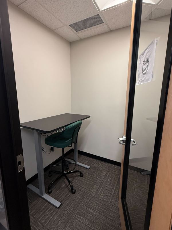 The Green Booth private phone booth featuring a sit-stand desk and green ergonomic stool for quiet video calls.
