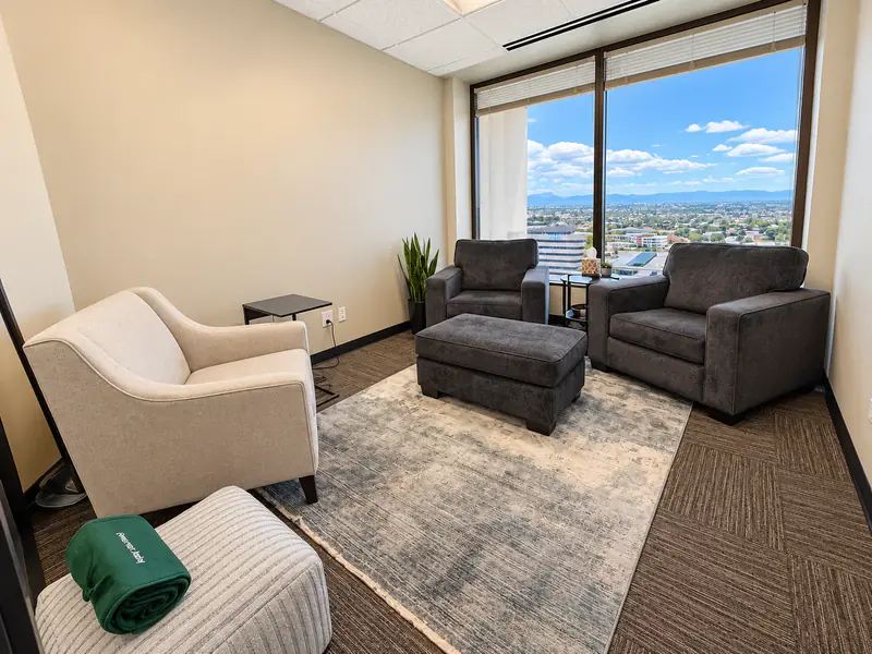 Cozy Huddle Hub private meeting room at Spoke Tower Suites featuring armchairs and panoramic city views.
