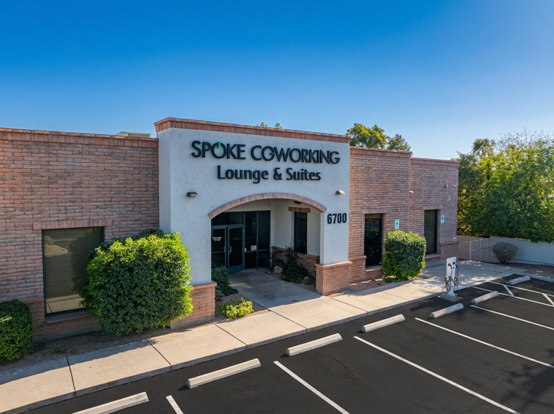 Exterior view of the Spoke Coworking Lounge & Suites building at 6700 with a brick facade and arched entrance.