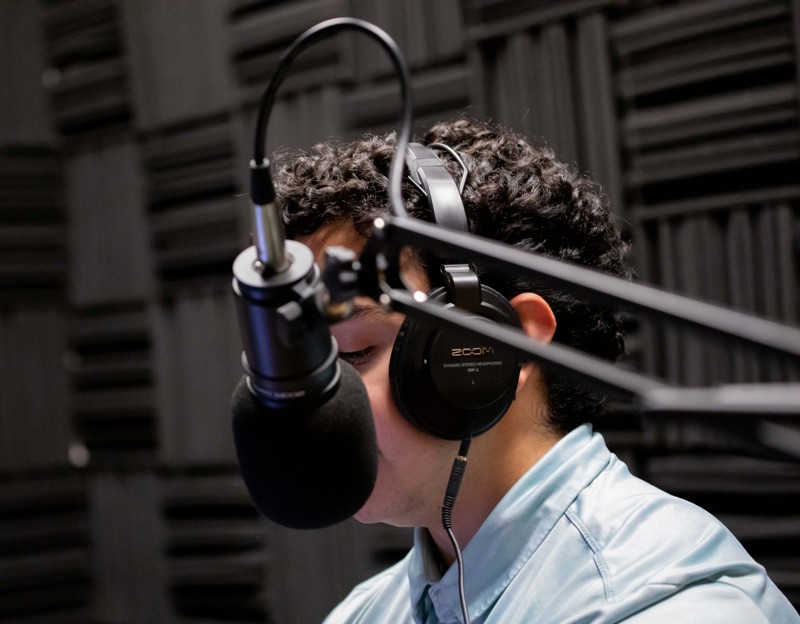A person recording in the professional podcast studio at Spoke Coworking Lounge & Suites in East Tucson.