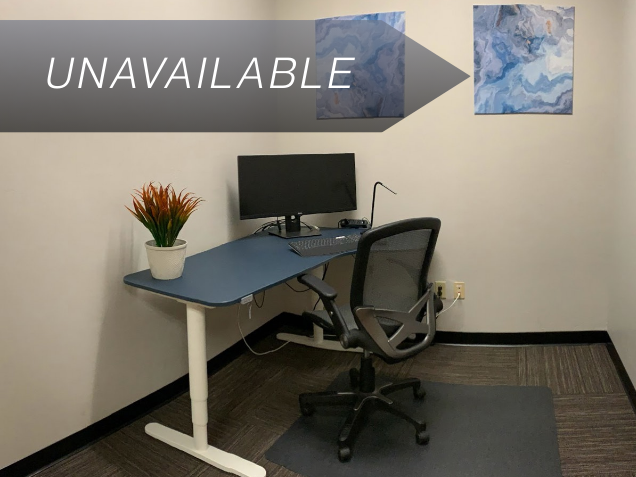Private mini suite office at Suite 114 with a sit-stand desk, curved monitor, and ergonomic chair for focused work.