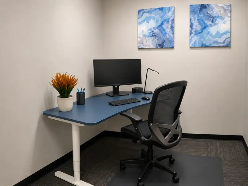 Private office Suite 114 with an adjustable sit-stand desk, ergonomic chair, and curved monitor for focused work.